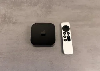 Apple TV einrichten: schwarzes Apple TV 4K neben einer silbernen Siri Remote auf einer grauen Fläche in Steinoptik