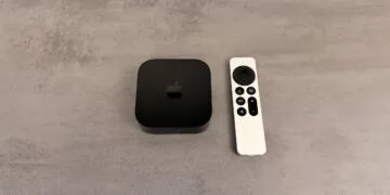 Apple TV einrichten: schwarzes Apple TV 4K neben einer silbernen Siri Remote auf einer grauen Fläche in Steinoptik