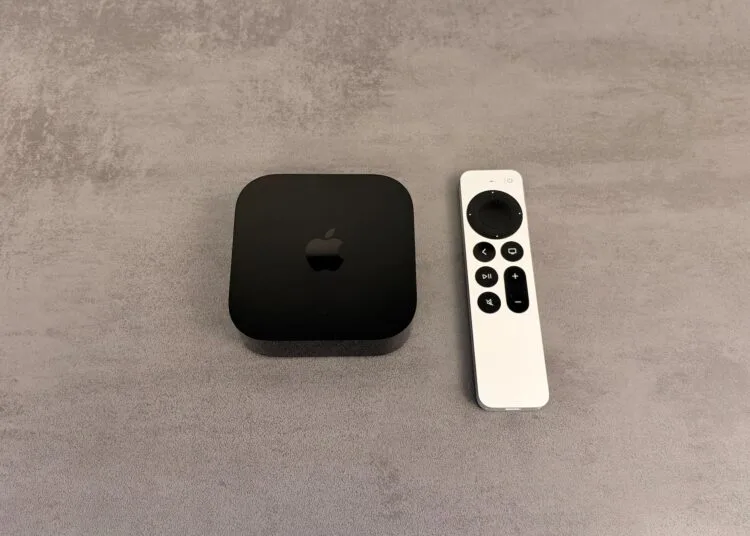 Apple TV einrichten: schwarzes Apple TV 4K neben einer silbernen Siri Remote auf einer grauen Fläche in Steinoptik