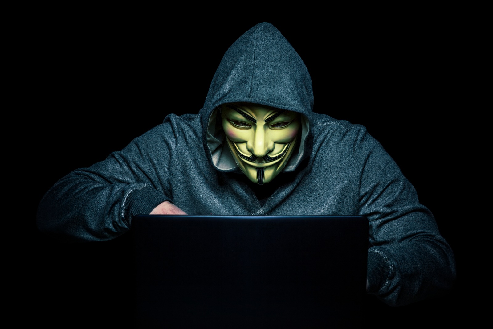 MILAN,ITALY, February, 2018: Hacker wear anonymus mask with notebook in the dark .