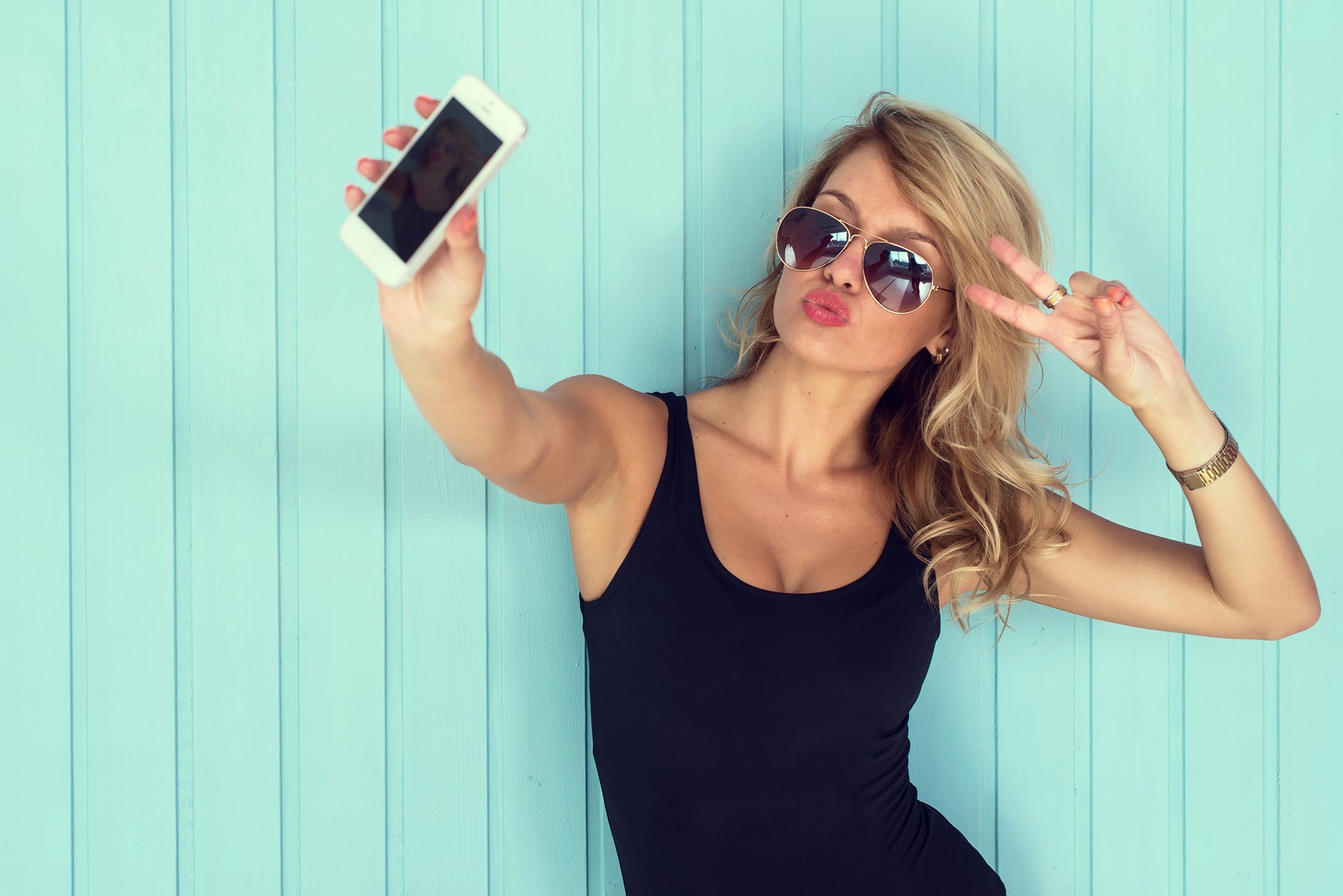blonde woman in bodysuit with perfect body taking selfie with smartphone  toned instagram filter
