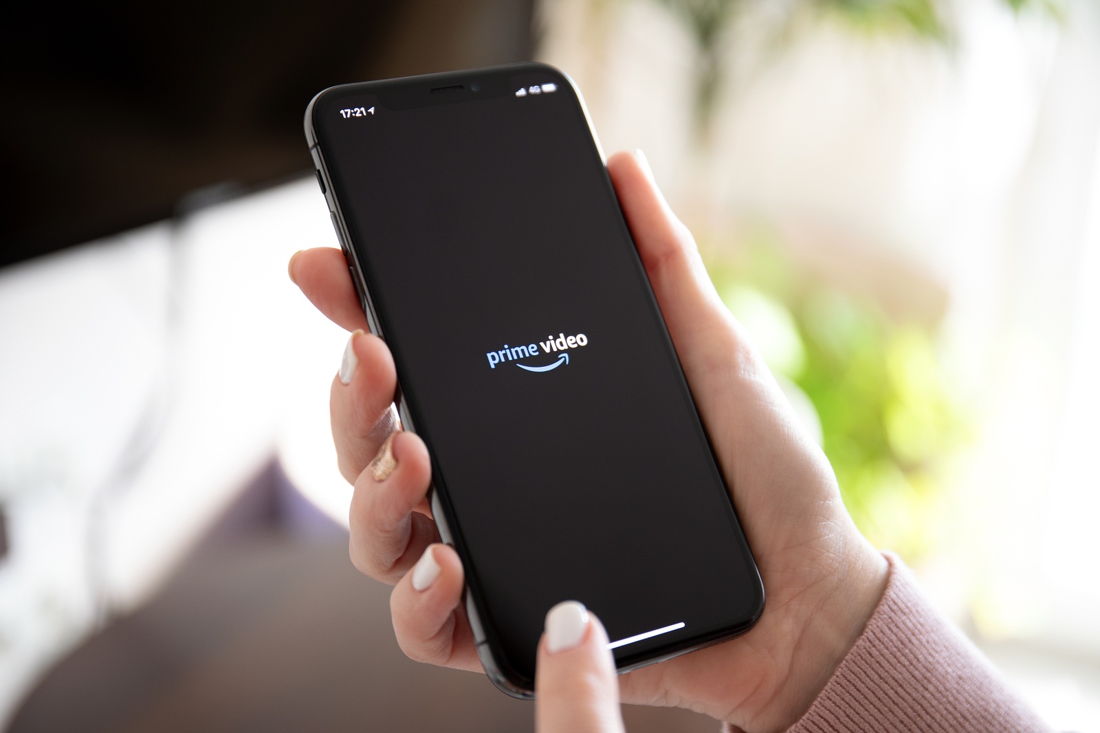 Anapa, Russia - February 20, 2019: Woman holding iPhone X with multinational entertainment company Amazon Prime Video provides streaming media and video on the screen.