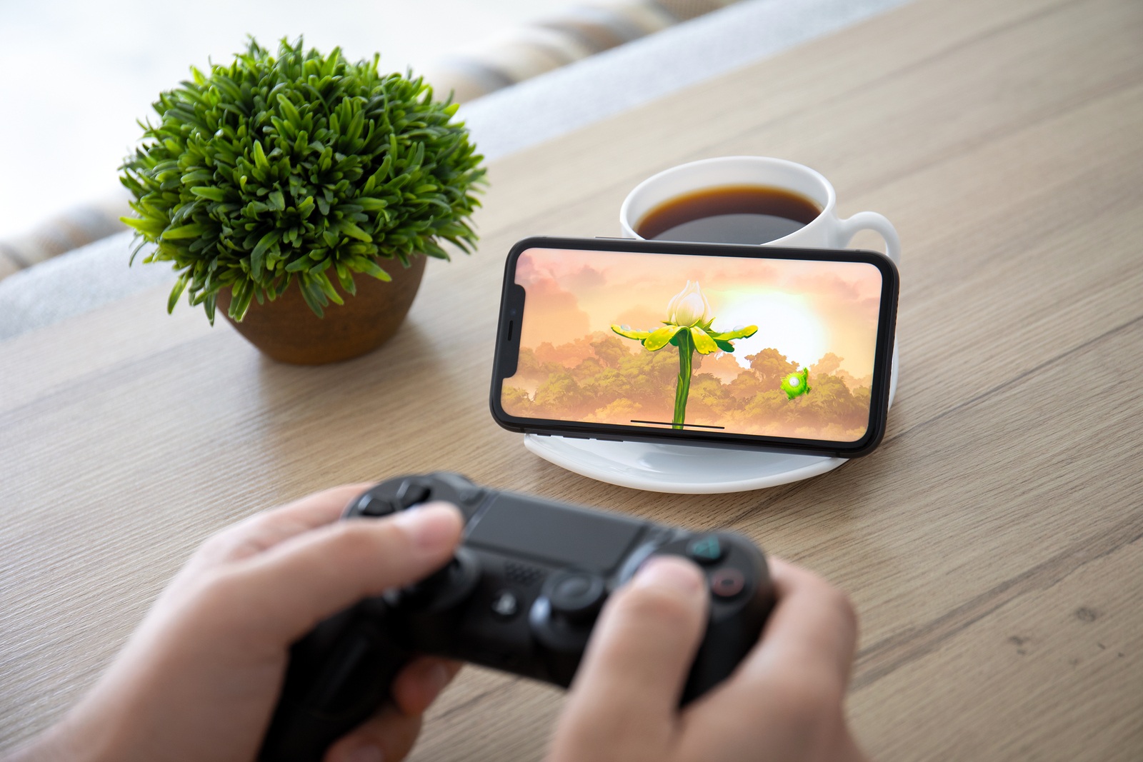 Anapa, Russia - October 2, 2019: Man hand holding Dualshock 4 play game Rayman Adventures in the screen on iPhone 11. Games Rayman Adventures was developer by the Ubisoft.