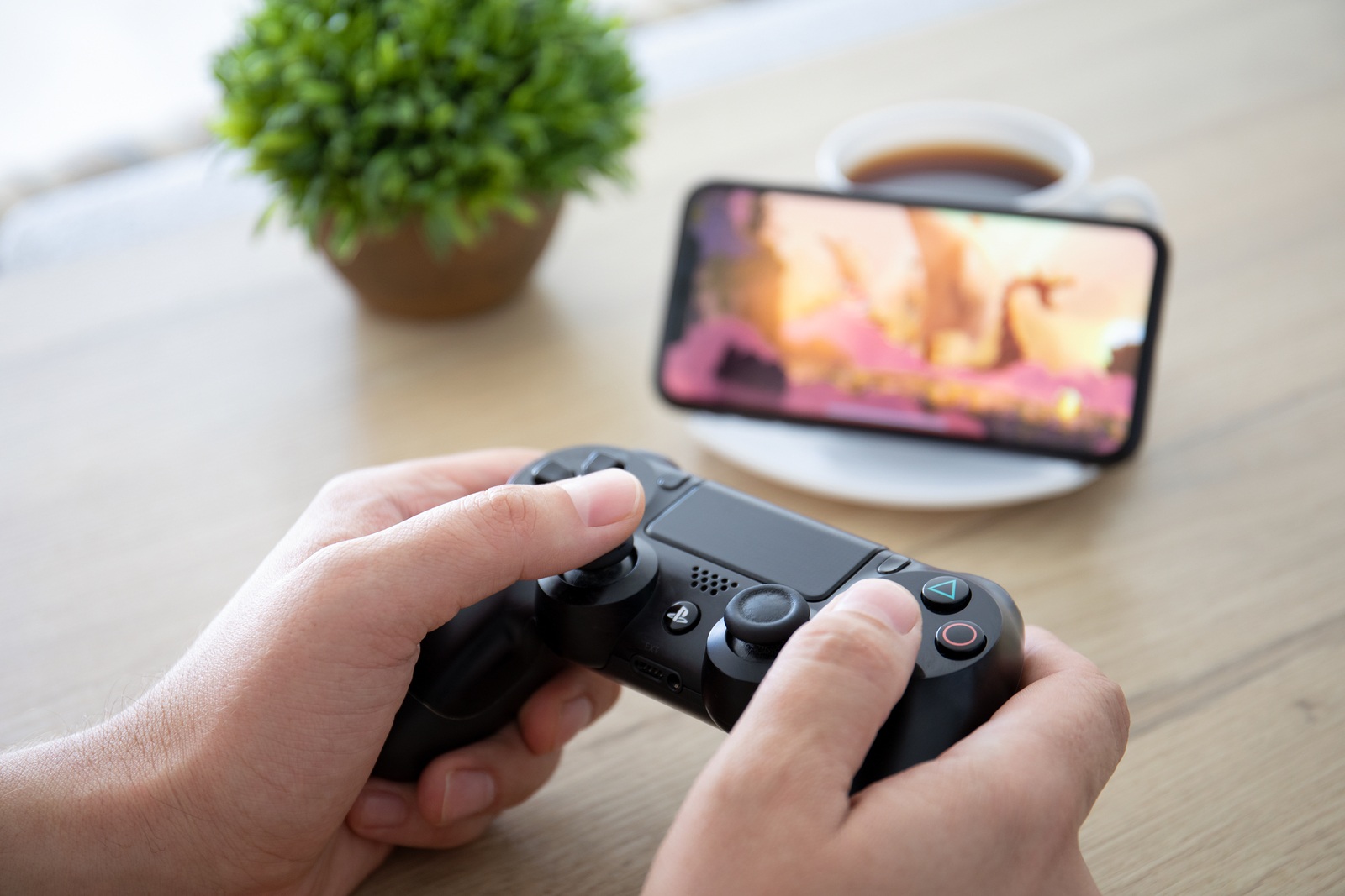 Anapa, Russia - October 2, 2019: Man hand holding Dualshock 4 play game Rayman Adventures in the screen on iPhone 11. Games Rayman Adventures was developer by the Ubisoft.