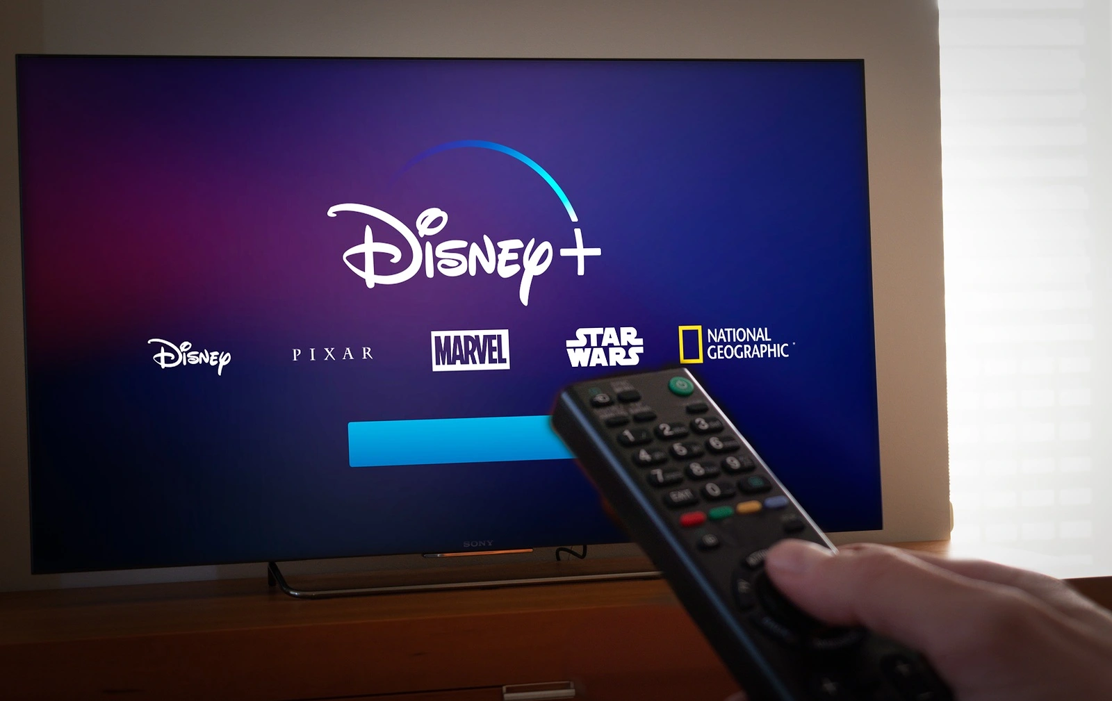 Barcelona, Spain. Jan 2019: Man holds a remote control With the new Disney+ screen on TV. Disney+ is an online video streaming subscription service, set to launch in the US in September.Illustrative editorial