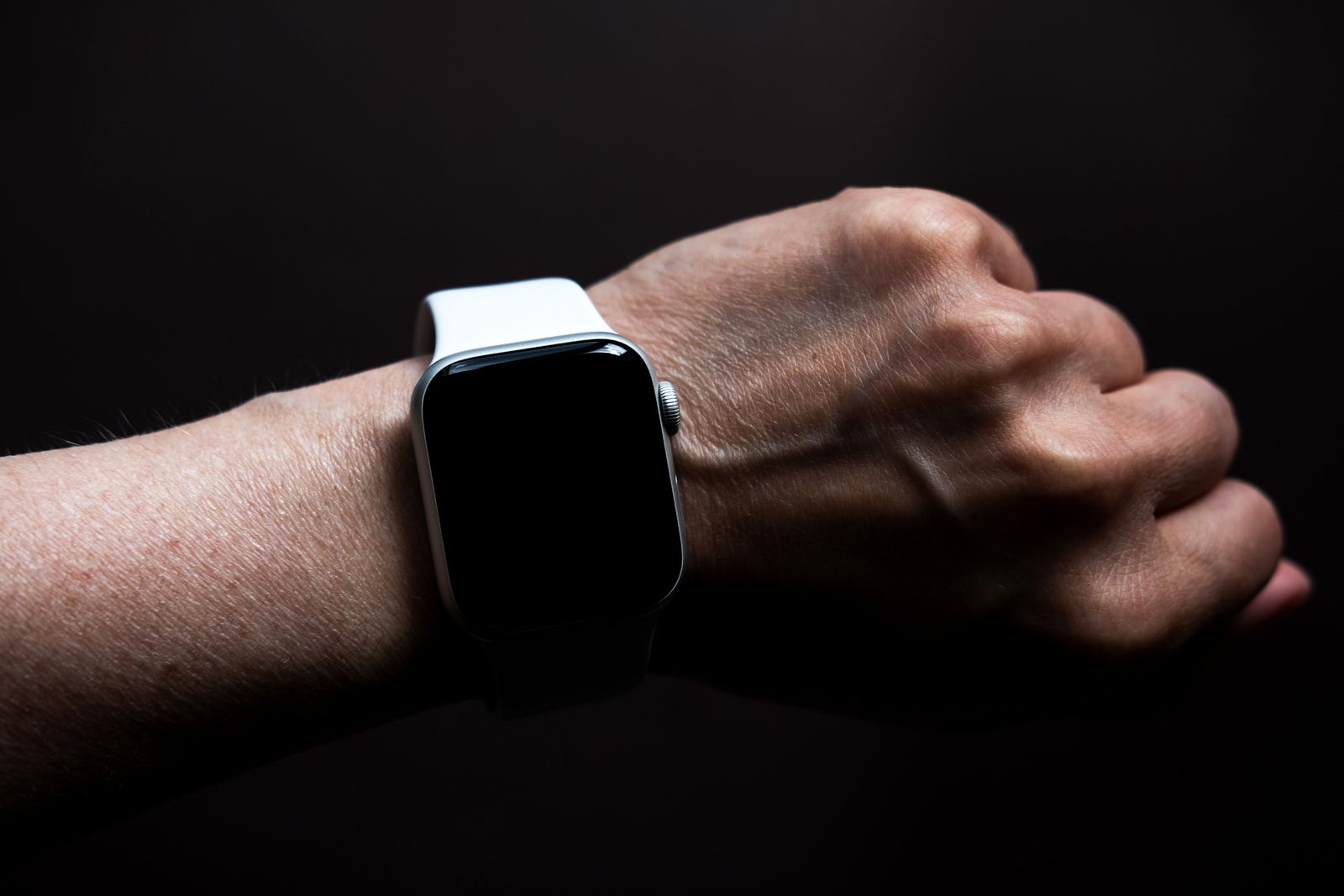 Chekhov, Russia - July 19, 2019: Apple Watch Series 4 white color with hand. A new watch from an Apple company closeup isolated on dark background