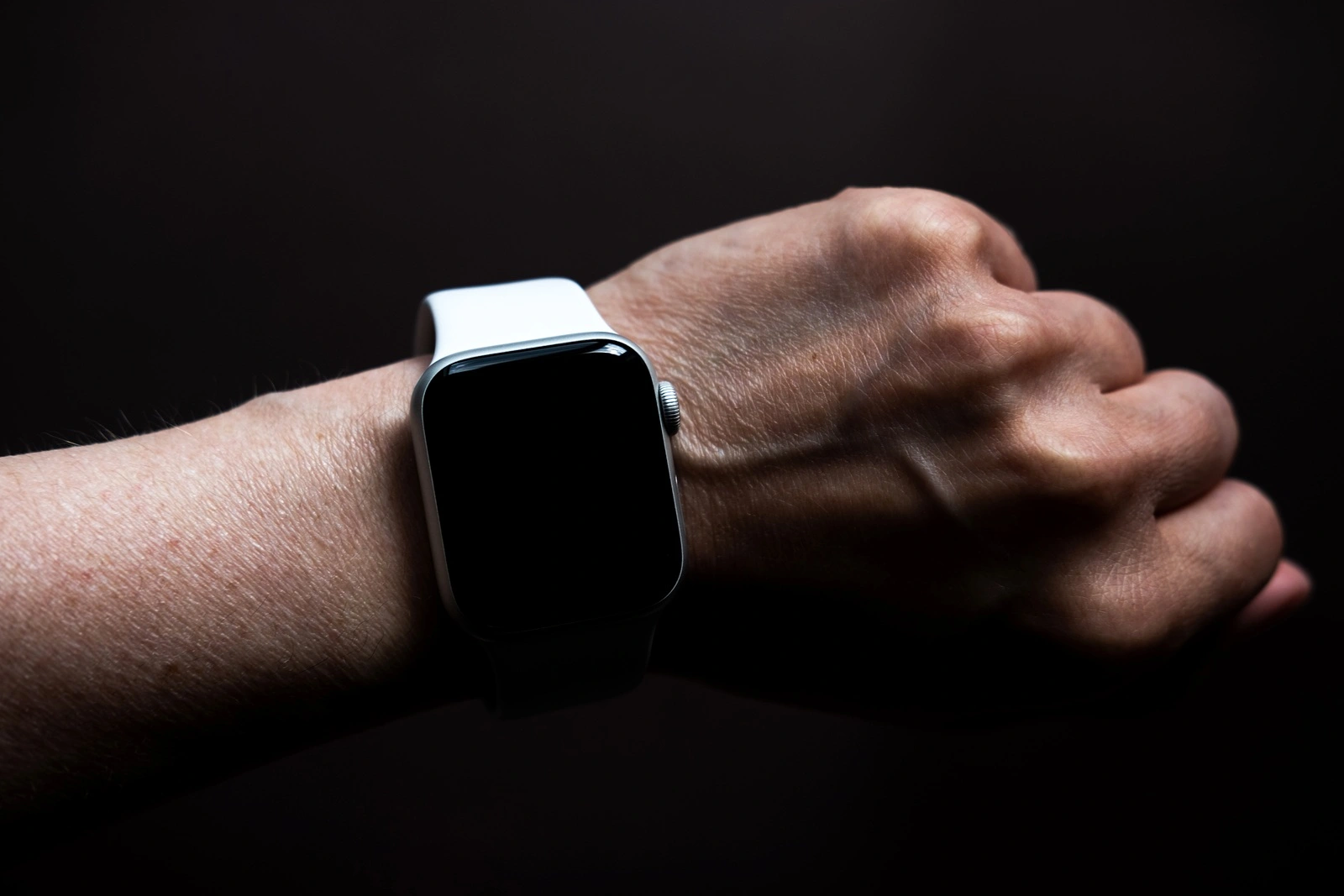 Chekhov, Russia - July 19, 2019: Apple Watch Series 4 white color with hand. A new watch from an Apple company closeup isolated on dark background