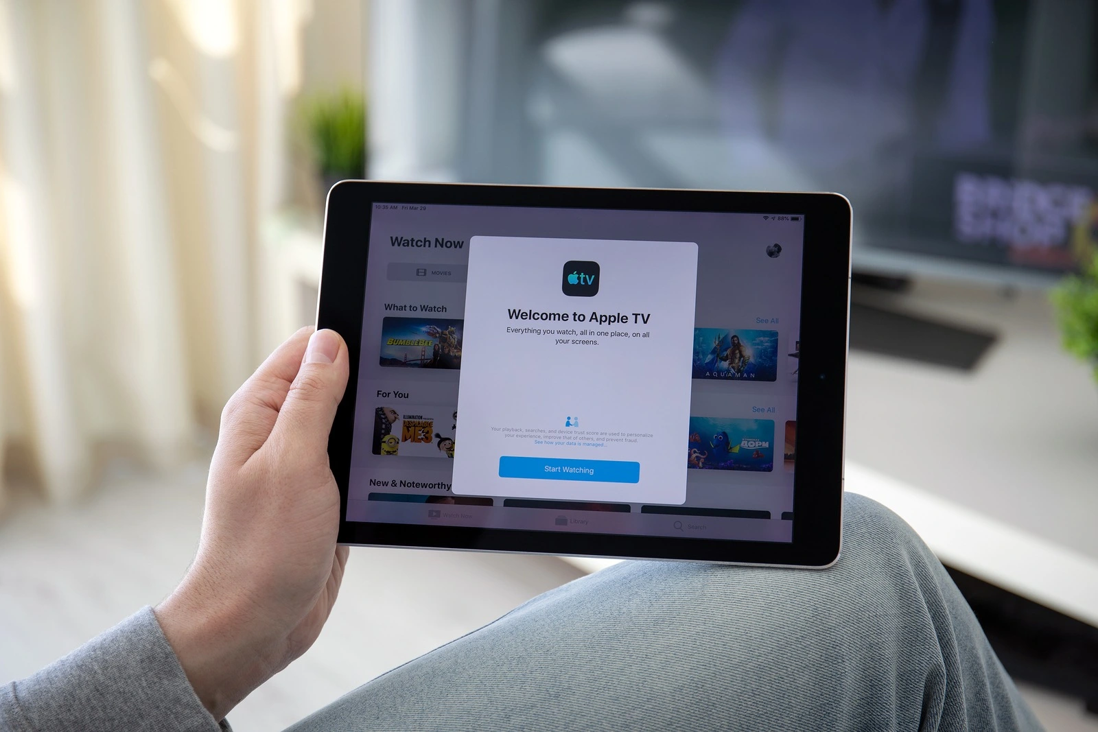 Anapa, Russia - March 29, 2019: Man holding iPad Pro with Apple TV app provides streaming movies and cable channel on the screen.