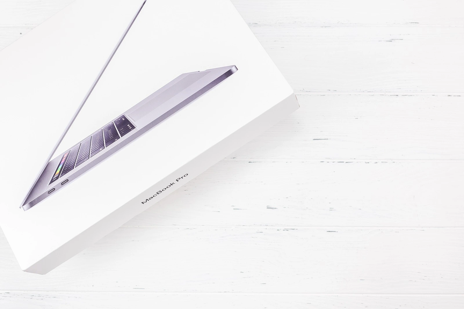 BERLIN, GERMANY - DECEMBER 09, 2018: The box of the latest Apple Macbook Pro laptop computer against white wooden background. Unboxing top view concept with copy space