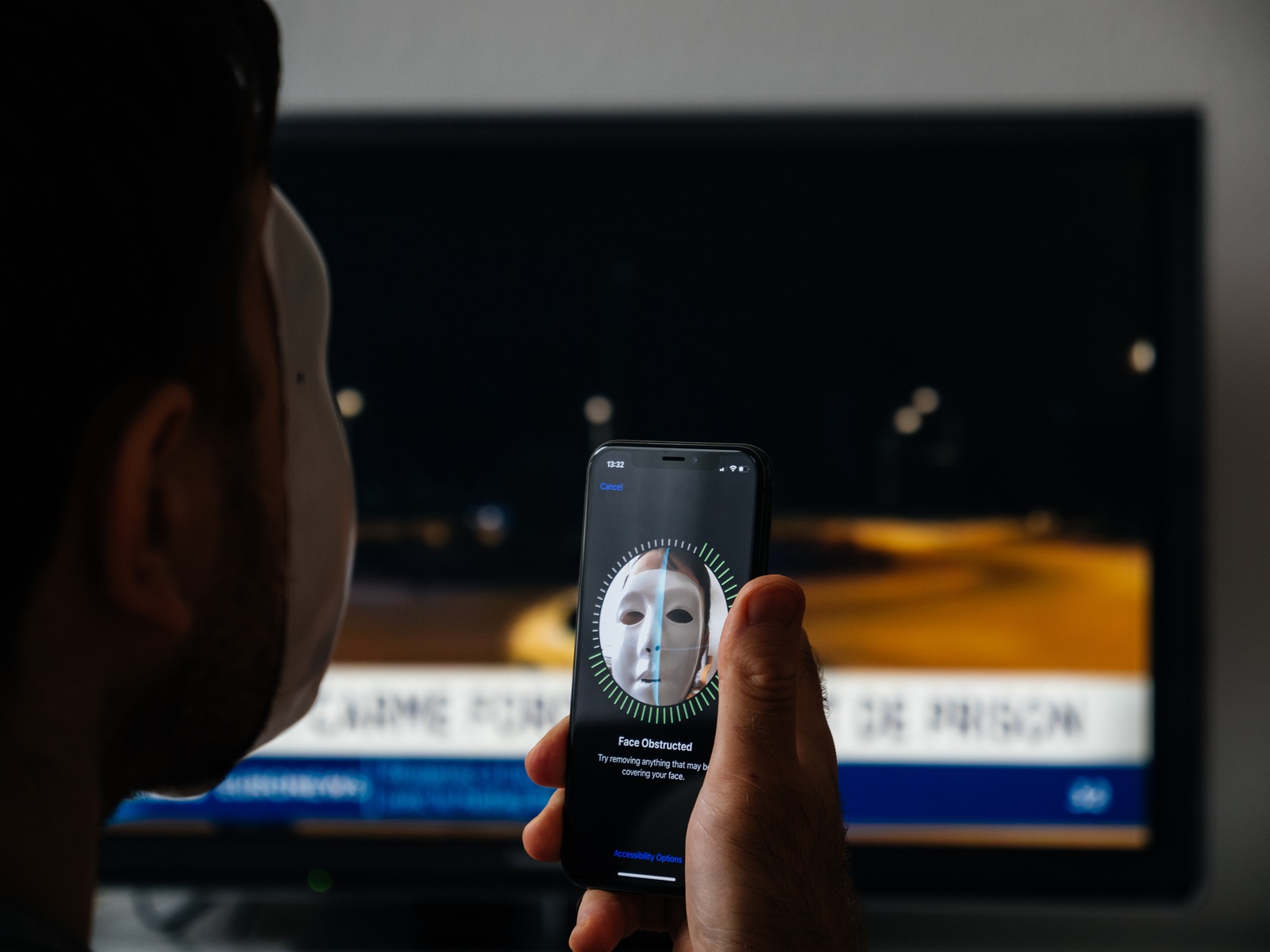 Paris, France - Nov 11, 2017: Rear view of face Obstructed message on display of new Apple iPhone XS Pro with Face ID anonymous hacker wearing a mask - data monitor in the background
