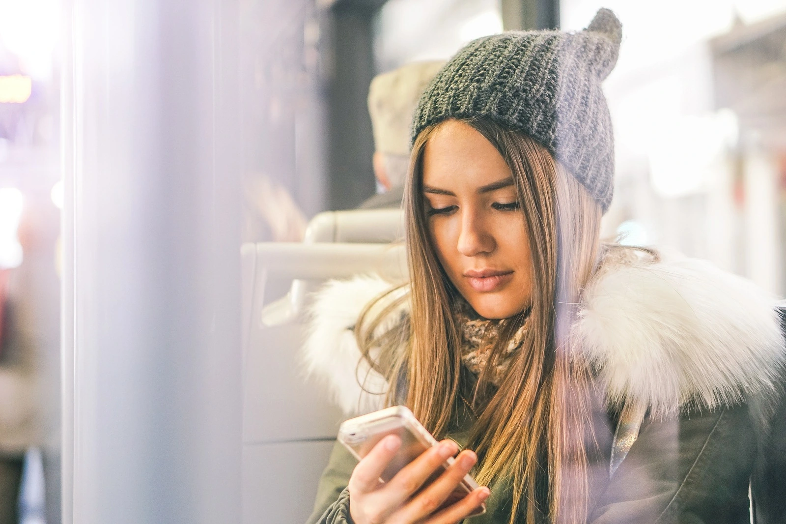 Young woman using her smart phone while sitting in a bus - Pretty girl connecting on her social network with her mobile phone - Concept of youth people addiction to new technology