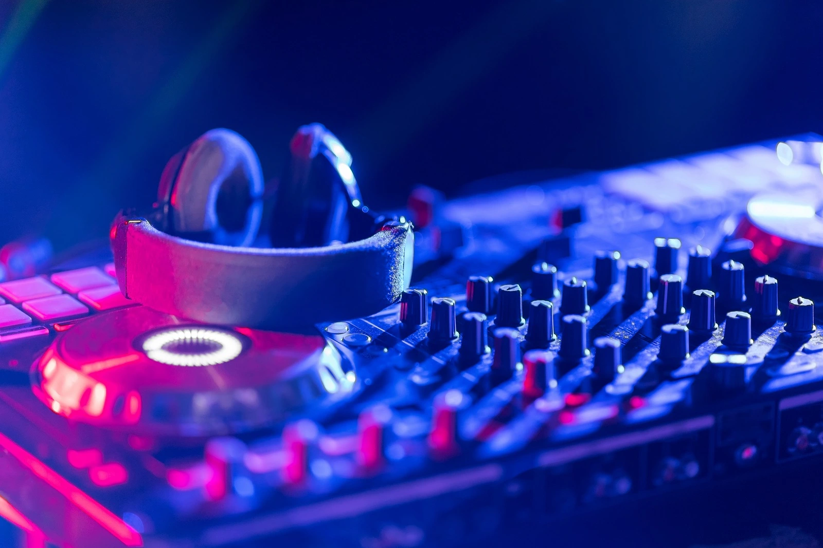 In selective focus of Pro dj controller.The DJ console cd mp4 deejay mixing desk Ibiza house music party in nightclub with colored disco lights.