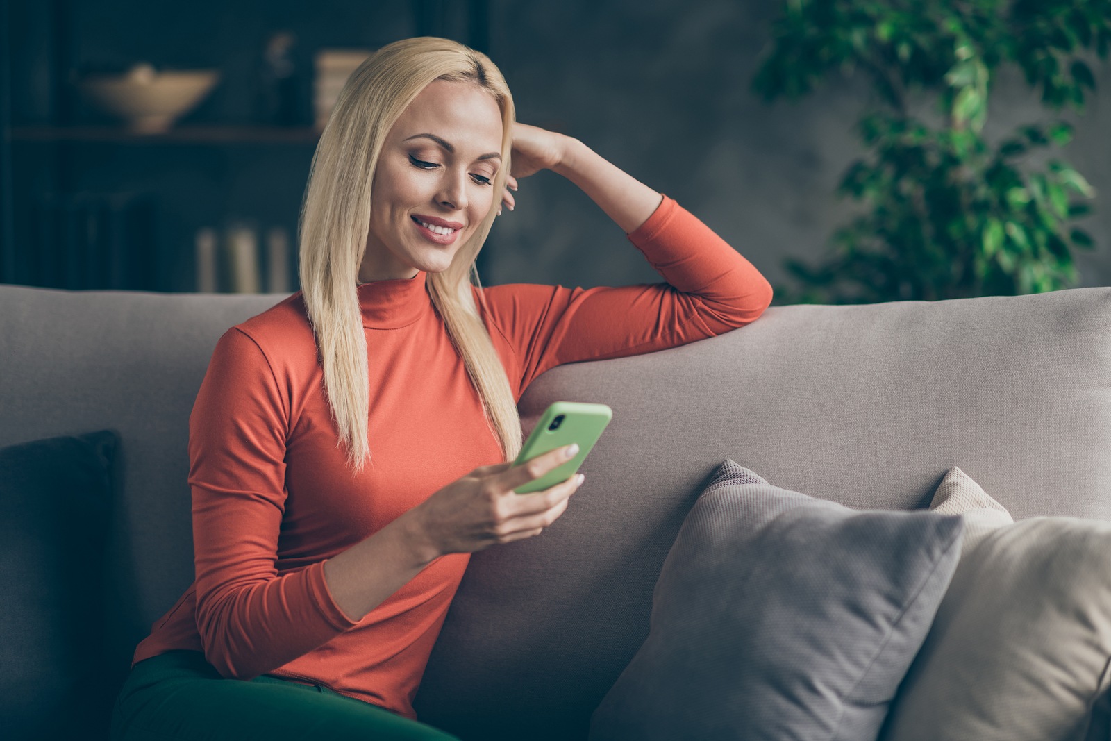 Photo of pretty blonde lady homey domestic mood texting telephone friends reading watching instagram post sitting comfy couch casual outfit living room indoors