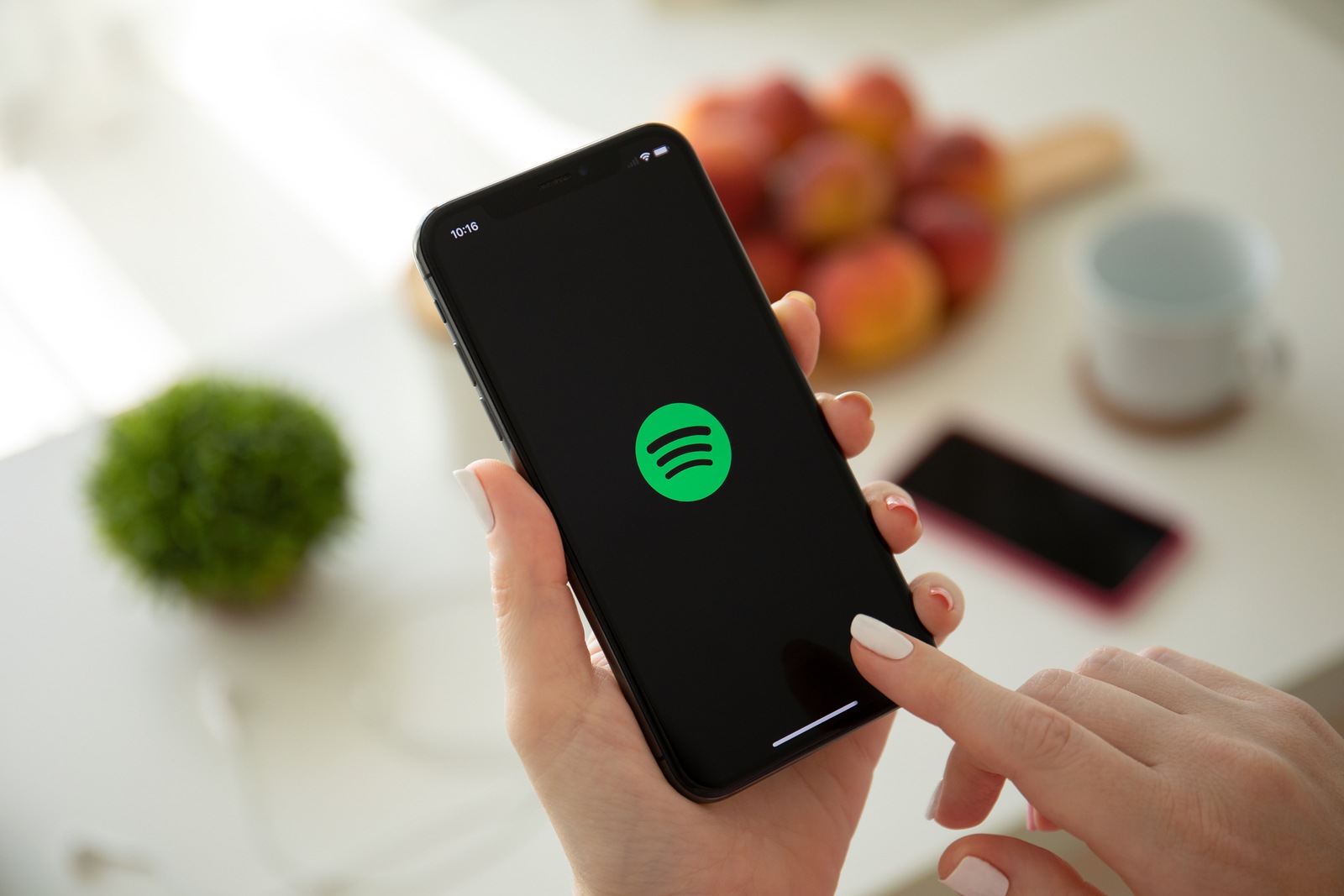Anapa, Russia - July 22, 2019: Woman holding iPhone X with music service Spotify on the screen. iPhone was created and developed by the Apple inc.