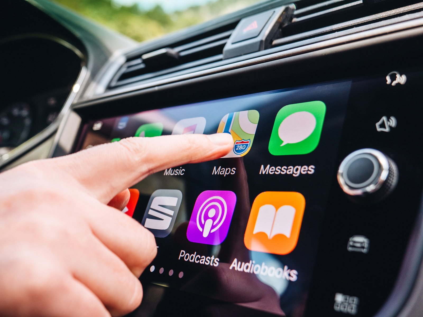 PALMA DE MALLORCA, SPAIN - MAY 10, 2018: Woman pressing Apple Maps button on the Apple CarPlay main screen in modern car dashboard while driving on Spanish holiday highway