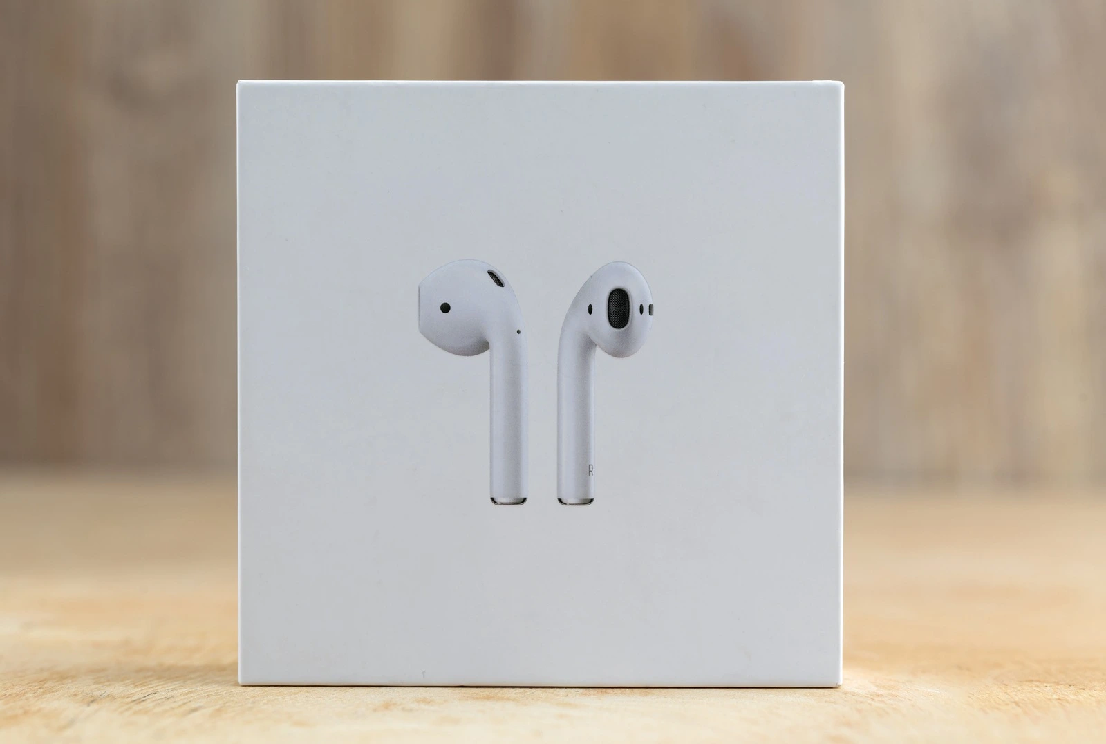 Rostov-on-Don, Russia - December 2018. Apple Airpods in a box on a wooden surface. New Airpods sealed in a box close-up on a wooden table.