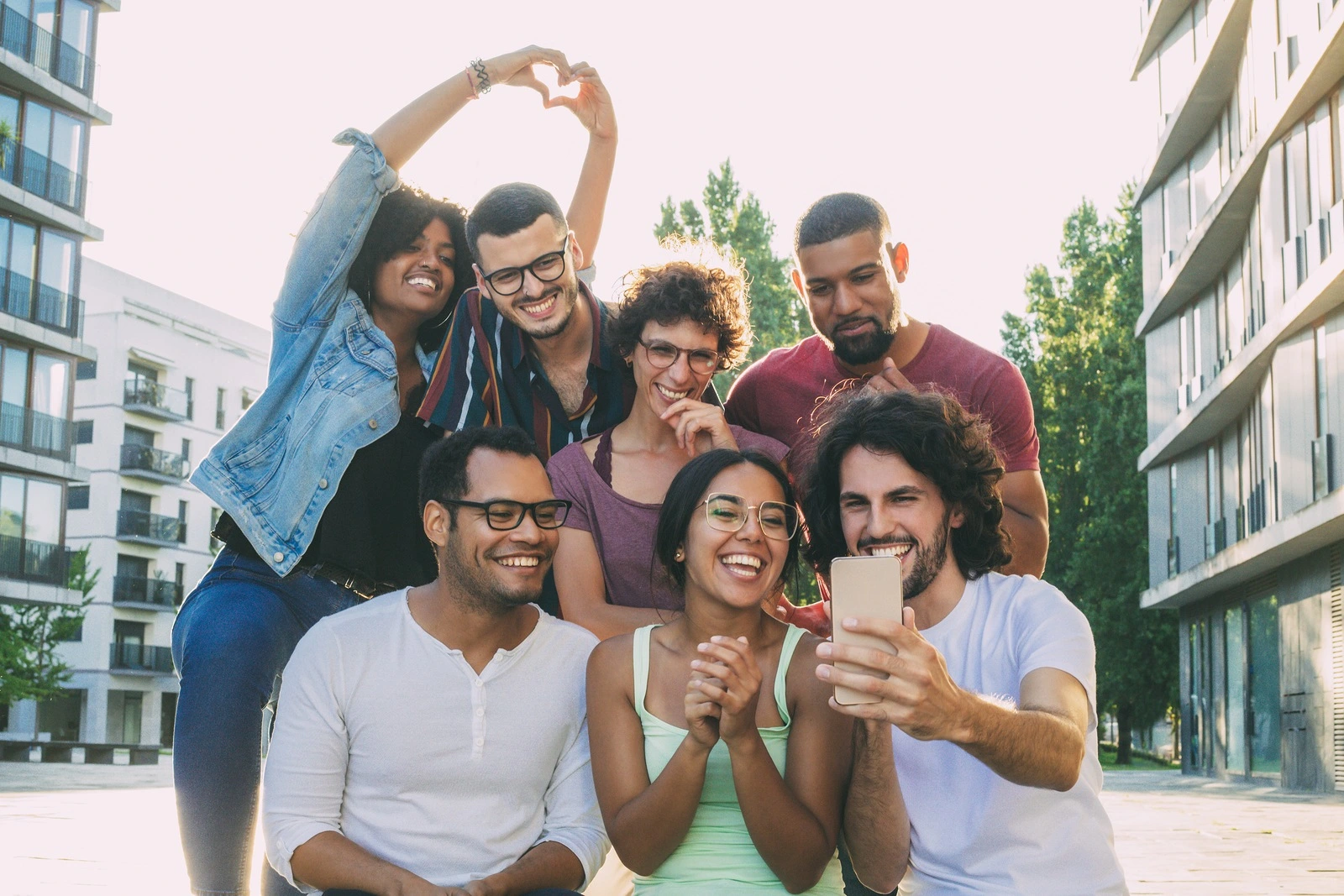 Excited overjoyed multiethnic people taking group selfie outside. Mix raced team of friends posing and laughing at phone camera. Group selfie concept