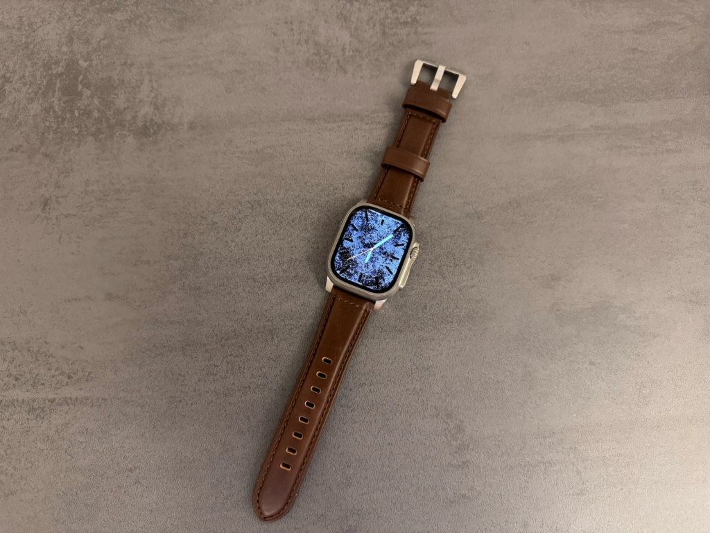 Nomad Lederarmband in Braun an einer Apple Watch Ultra auf grauem Hintergrund