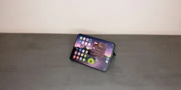 iPhone Widgets einrichten: aufgeklapptes iPhone mit iOS 27 im Querformat, aufgestellt auf einem grauen Tisch, mit App-Symbolen und Widgets für Musik und eine App auf dem Home-Bildschirm