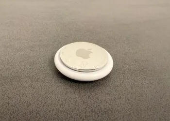 Apple KI-Pin: ein AirTag als Größenvergleich auf grauer Fläche