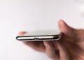 Symbolic image for the iPhone 20: iPhone in hand, view of the underside with speaker grille and connector.