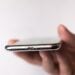 Symbolbild zum iPhone 20: iPhone in der Hand, Blick auf Unterseite mit Lautsprechergitter und Anschluss