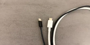 USB-C-Kabel am Mac: ein schwarzes, umflochtenes USB-C-Kabel ohne Kennzeichnung neben einem weißen Kabel mit Thunderbolt-Logo auf dem Stecker