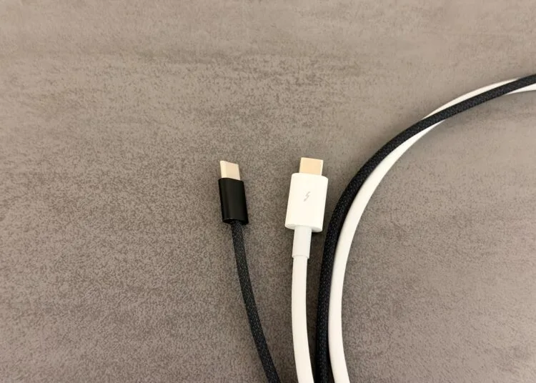USB-C-Kabel am Mac: ein schwarzes, umflochtenes USB-C-Kabel ohne Kennzeichnung neben einem weißen Kabel mit Thunderbolt-Logo auf dem Stecker