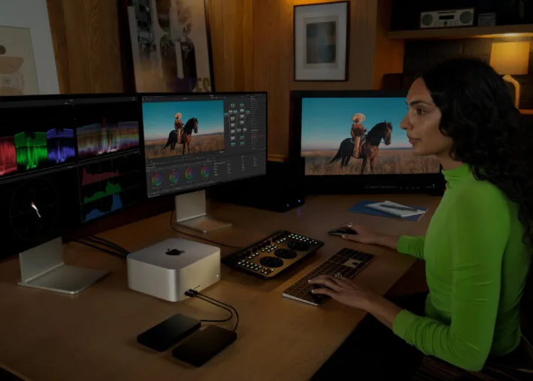 Arbeitsplatz mit Mac Studio und drei externen Displays, eine Person bearbeitet Video an Tastatur und Farbkorrektur-Panel