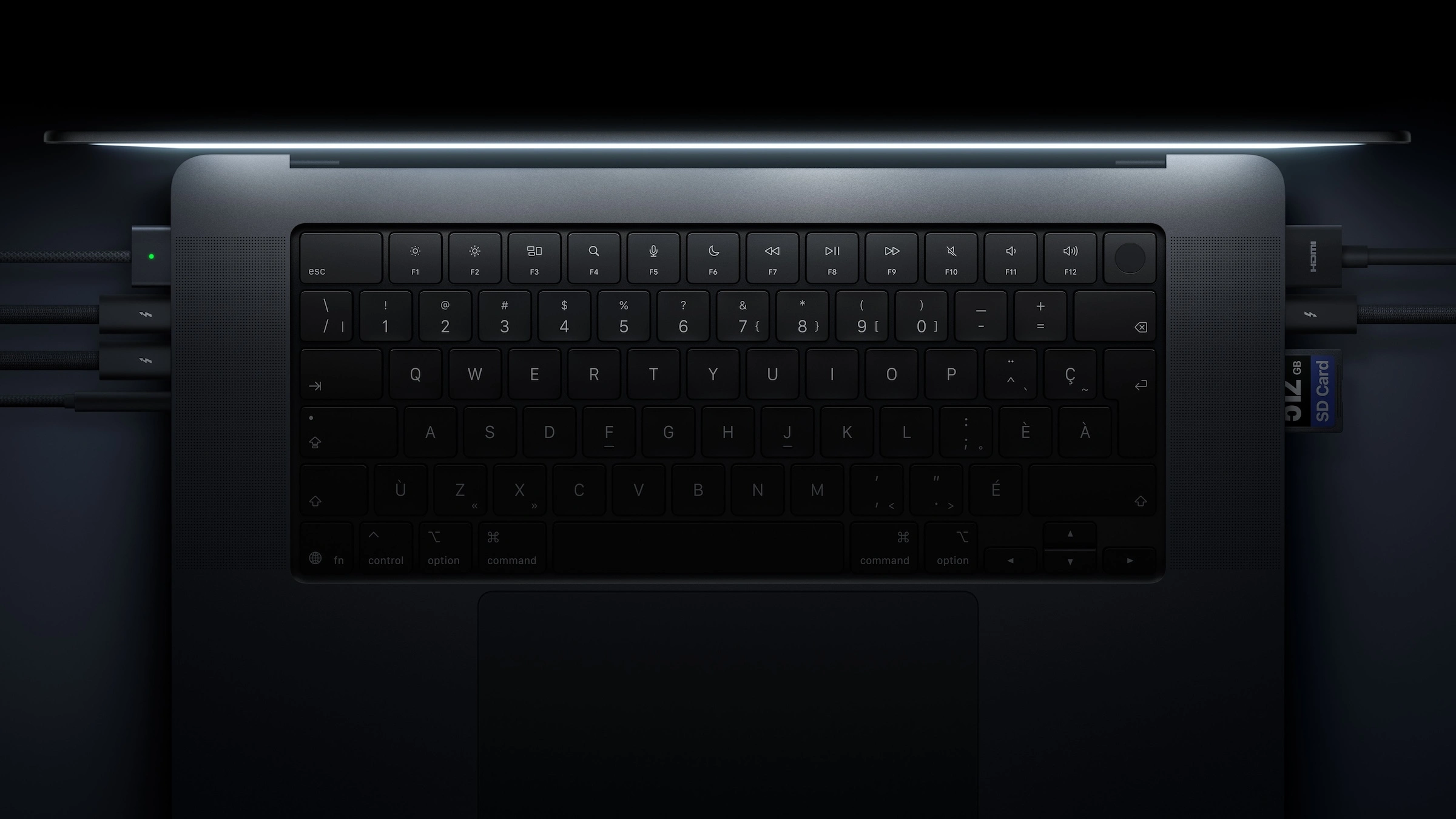 MacBook Pro mit PROLED XDR Display von oben mit Tastatur, links Kabel an MagSafe und Thunderbolt, rechts an HDMI und Thunderbolt sowie eine SD-Karte