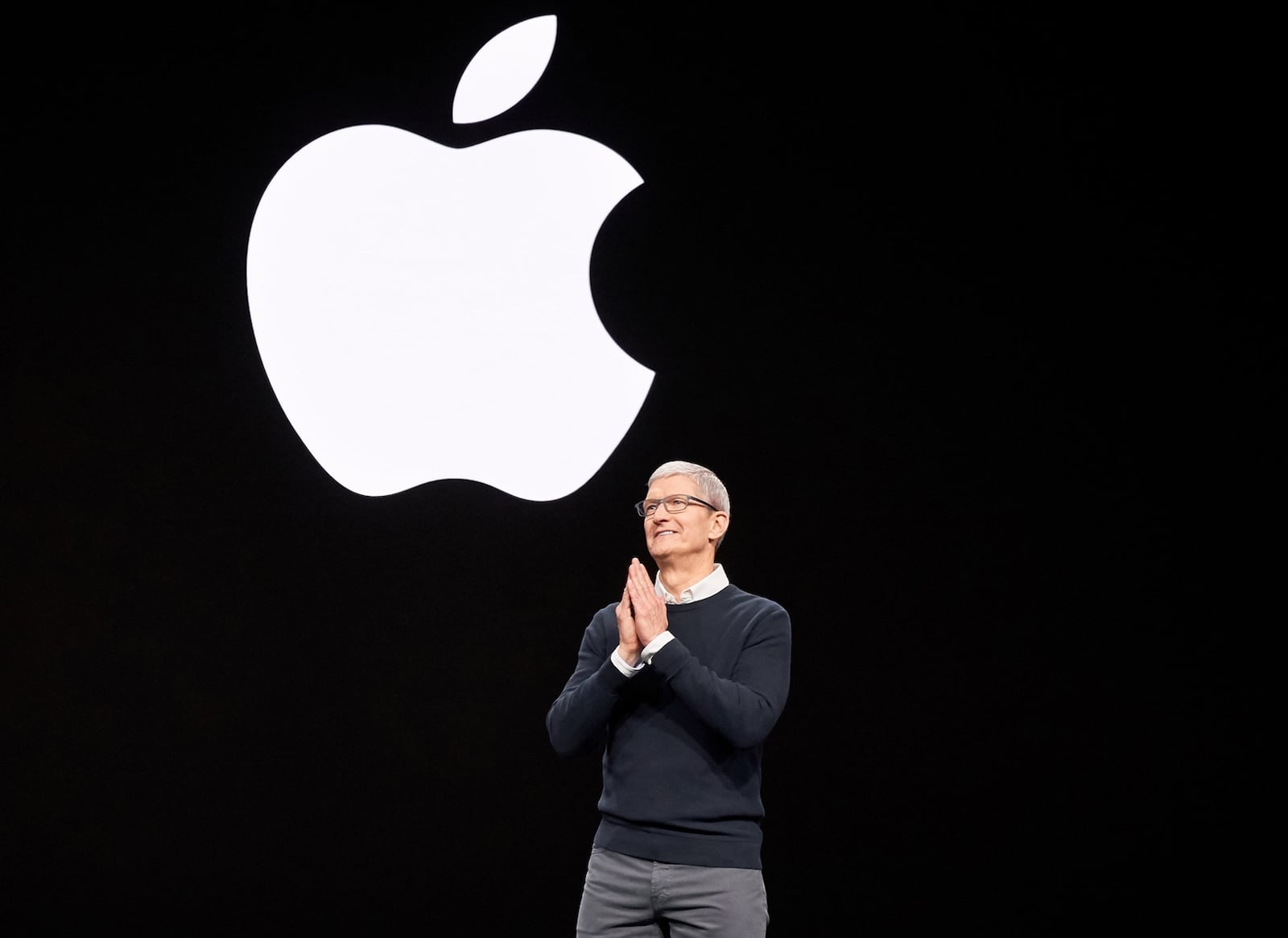 Tim Cook on stage in front of an illuminated Apple logo – taking stock after 15 years as Apple CEO