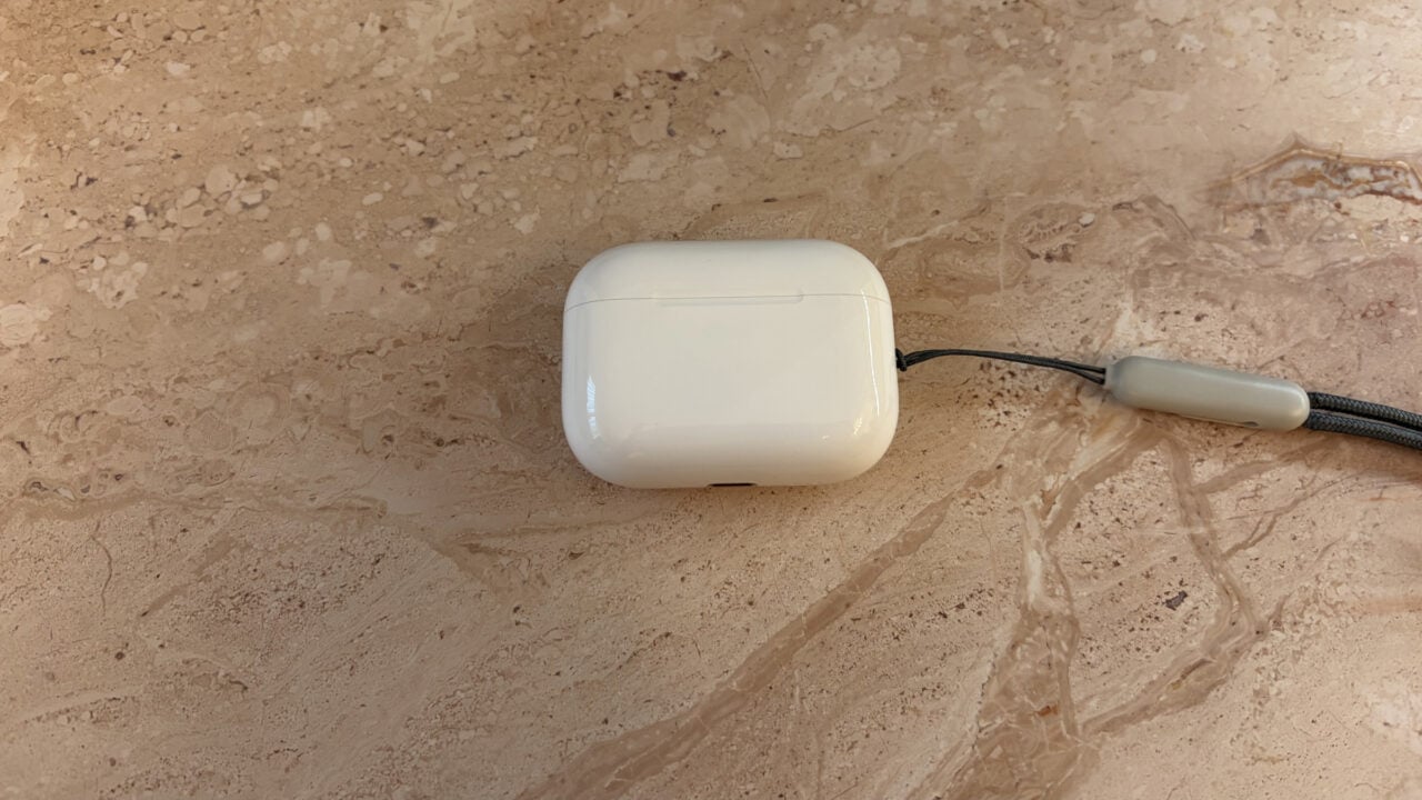 Geschlossenes Ladecase der AirPods Pro 3 mit Trageschlaufe auf hellem Marmor, Modell ohne Kameras