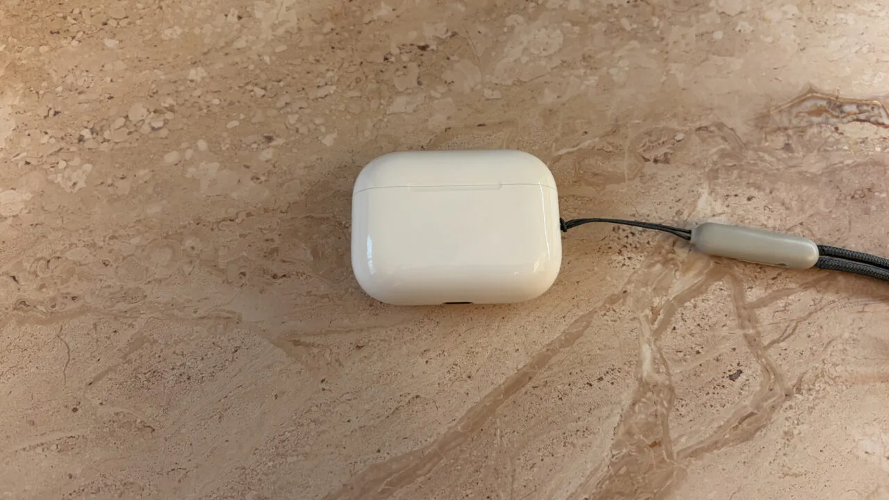 Geschlossenes Ladecase der AirPods Pro 3 mit Trageschlaufe auf hellem Marmor, Modell ohne Kameras