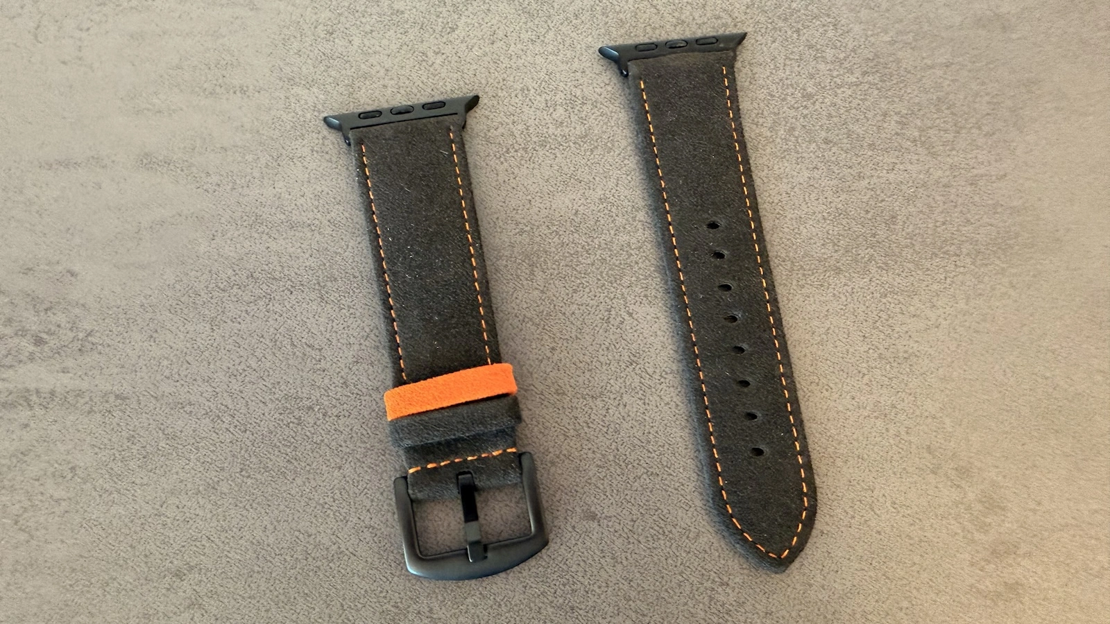 Beide Hälften des Armbands aus dem Alcantara Set mit orangefarbenen Ziernähten, schwarzer Dornschließe und Lochreihe