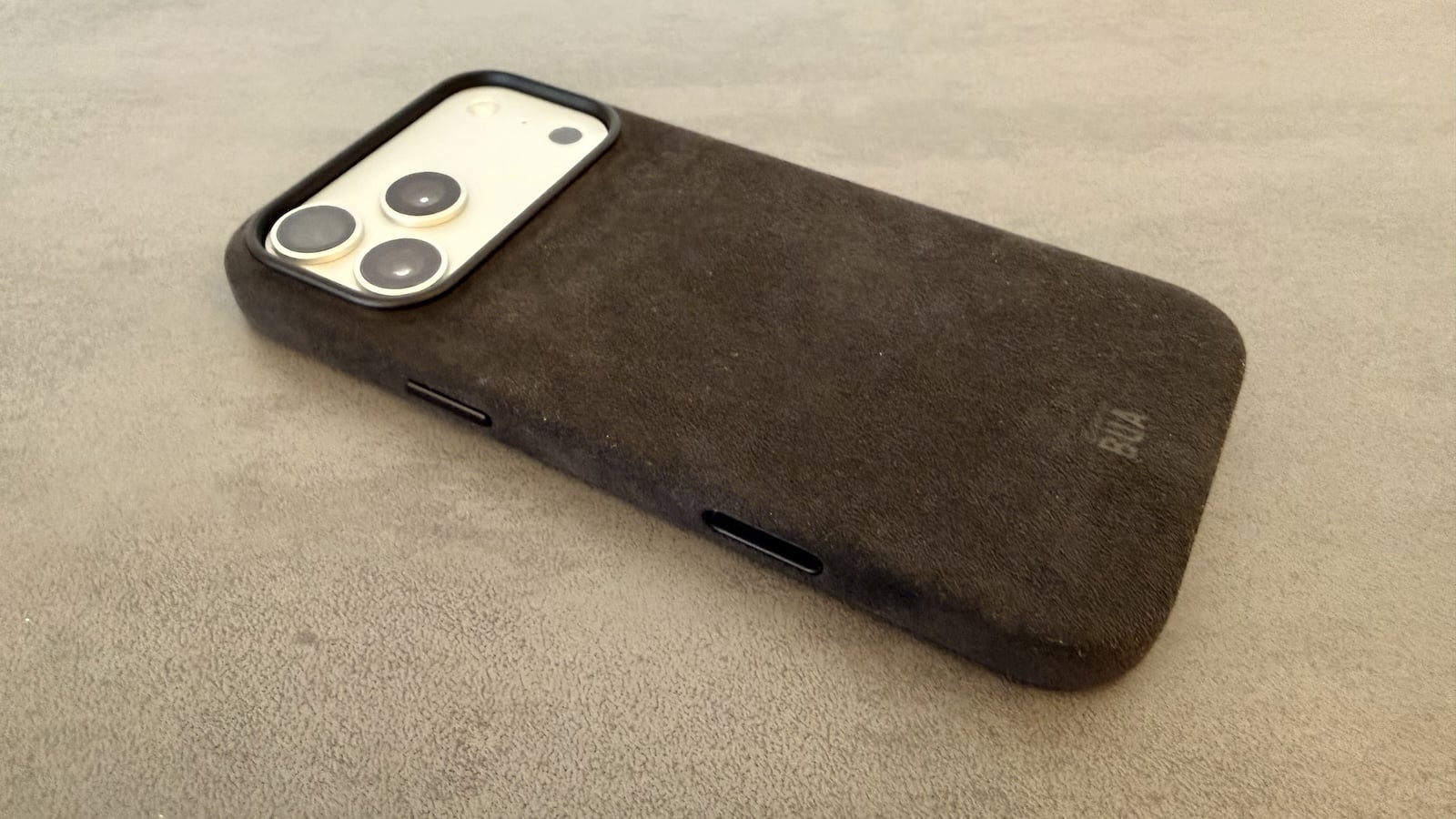 iPhone in the case from the Alcantara set, seen at an angle with the textile surface and button cutouts visible