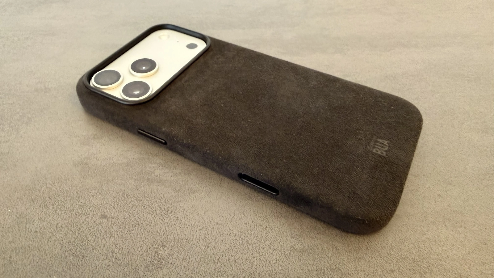 iPhone in der Hülle aus dem Alcantara Set, schräg von der Seite mit sichtbarer Textiloberfläche und Tastenaussparungen