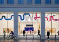 Symbolbild zu Apple Aktie Jefferies: Beleuchteter Apple Store in der Rosenthaler Straße in Berlin am Abend mit Passanten davor