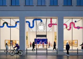 Symbolbild zu Apple Aktie Jefferies: Beleuchteter Apple Store in der Rosenthaler Straße in Berlin am Abend mit Passanten davor