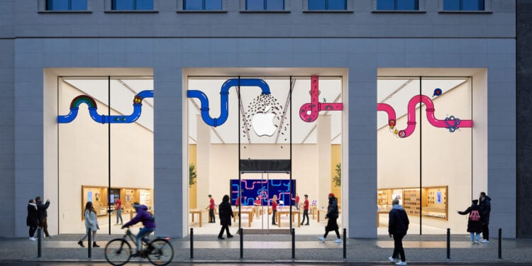 Symbolbild zu Apple Aktie Jefferies: Beleuchteter Apple Store in der Rosenthaler Straße in Berlin am Abend mit Passanten davor