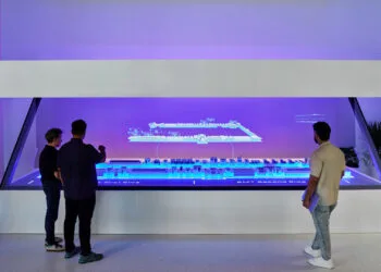 Drei Personen betrachten im Schulungswerk von Apple Houston eine holografische Darstellung einer Fertigungsstraße