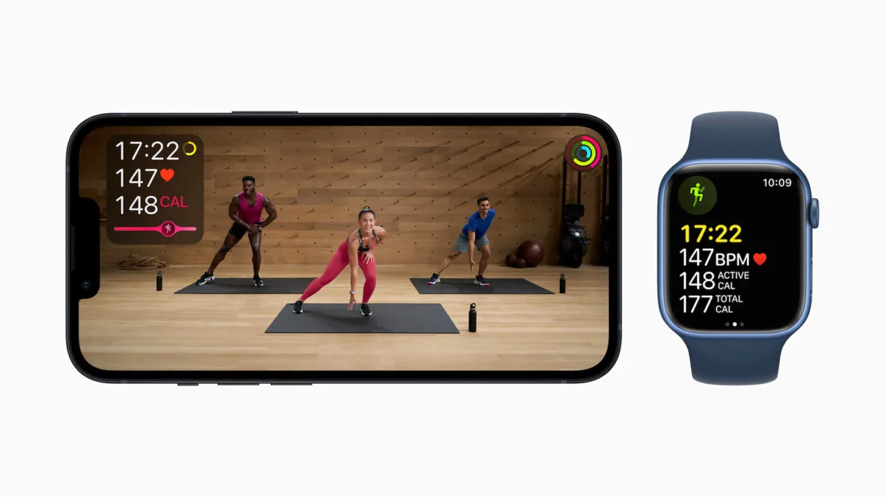 Apple Fitness+ Training auf einem iPhone mit drei Trainern im Studio, daneben eine Apple Watch mit Herzfrequenz und Kalorienwerten