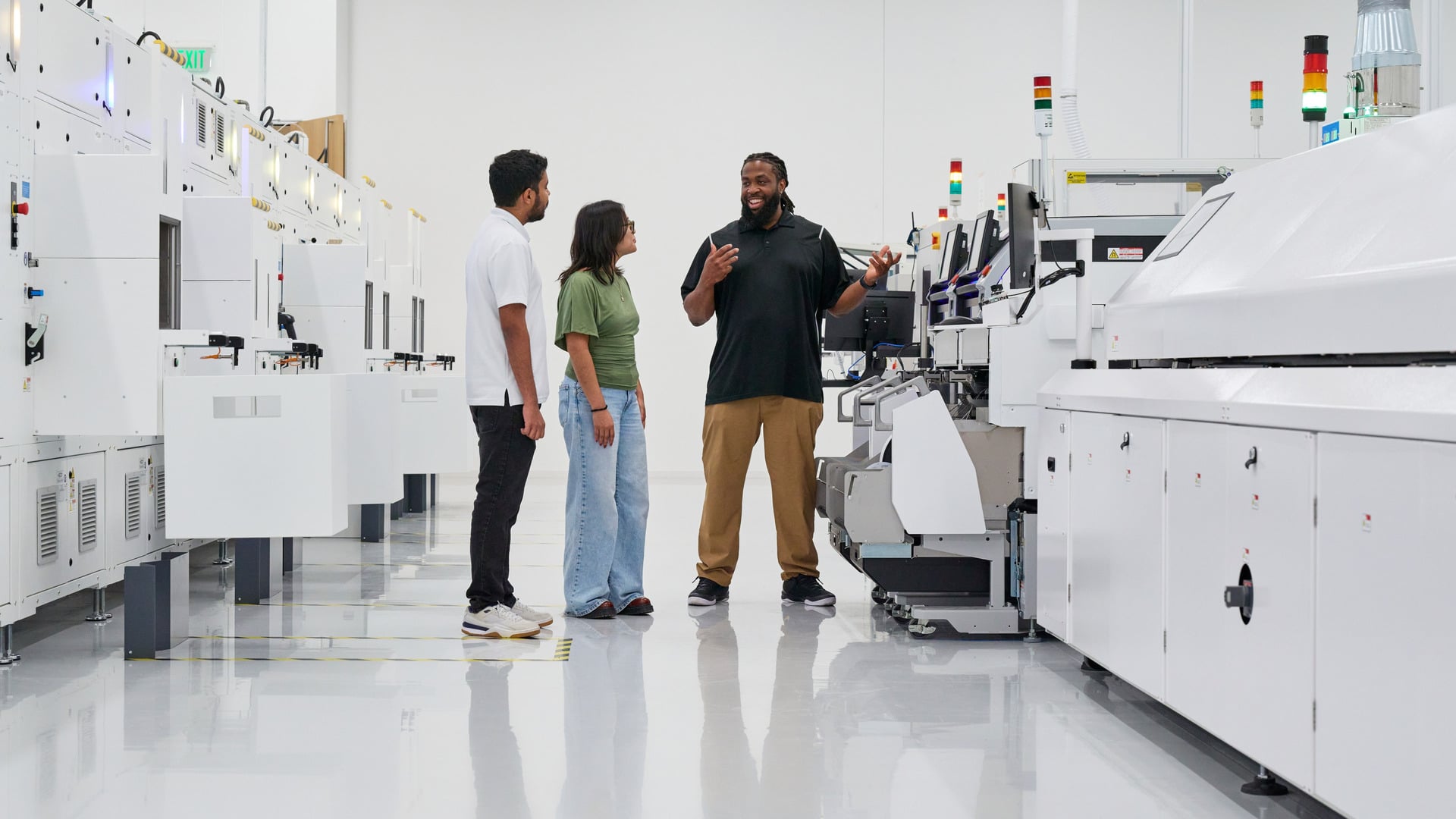 Drei Personen stehen zwischen Fertigungsanlagen in der Halle von Apple Houston, in der auch der Mac mini entstehen soll