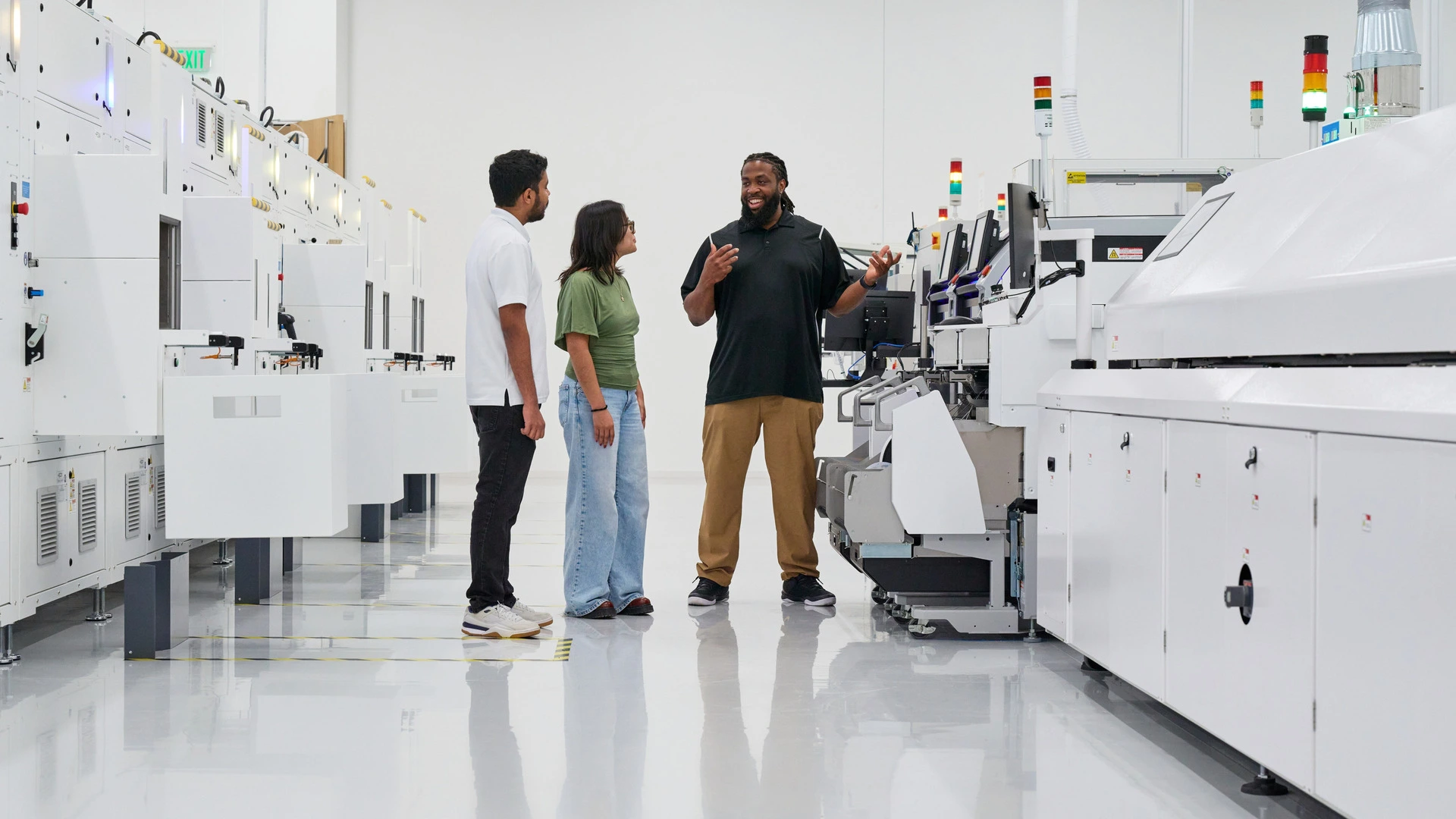 Drei Personen stehen zwischen Fertigungsanlagen in der Halle von Apple Houston, in der auch der Mac mini entstehen soll