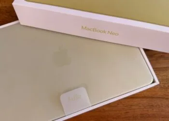 Halb geöffnete Verpackung des MacBook Neo in Citrus, das Gerät liegt noch in der Schutzhülle im Karton