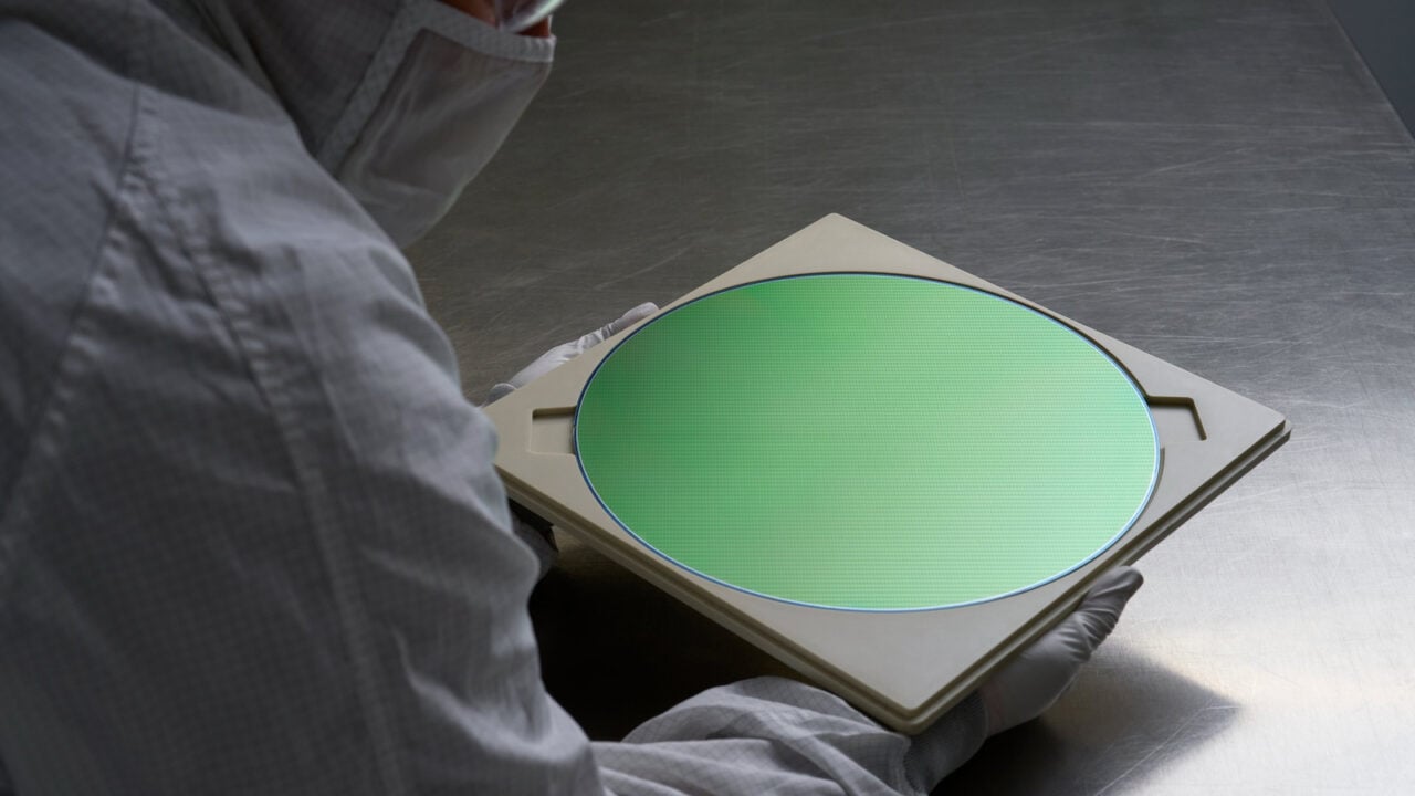 Mitarbeiter im Reinraumanzug hält einen Halbleiterwafer, wie er auch für die iPhone 18 Pro Chips TSMC fertigt