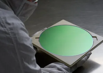 Mitarbeiter im Reinraumanzug hält einen Halbleiterwafer, wie er auch für die iPhone 18 Pro Chips TSMC fertigt