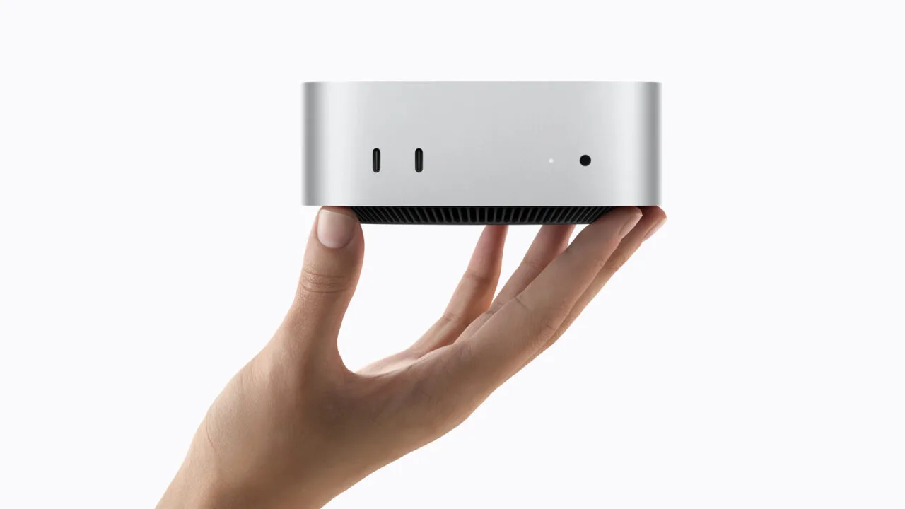 Mac mini M6 in Silber wird von einer Hand gehalten, Vorderseite mit zwei USB-C-Anschlüssen sichtbar