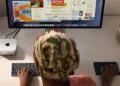Mac mini M6 neben einem Studio Display auf einem Schreibtisch, davor eine Person an Tastatur und Trackpad