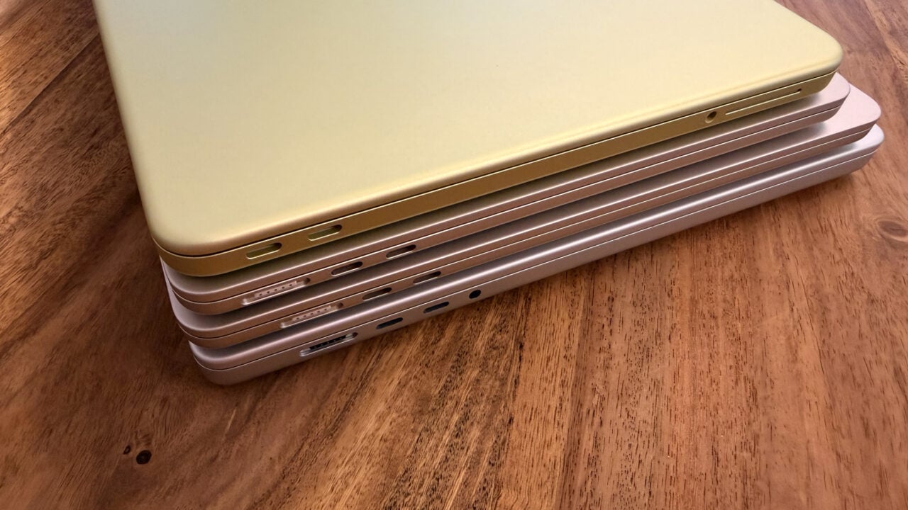 Vier gestapelte MacBooks von der Anschlussseite mit MagSafe 3 und USB-C, wobei je nach Modell ein anderes MacBook Netzteil die volle Ladegeschwindigkeit erreicht