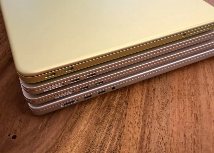 Vier gestapelte MacBooks von der Anschlussseite mit MagSafe 3 und USB-C, wobei je nach Modell ein anderes MacBook Netzteil die volle Ladegeschwindigkeit erreicht
